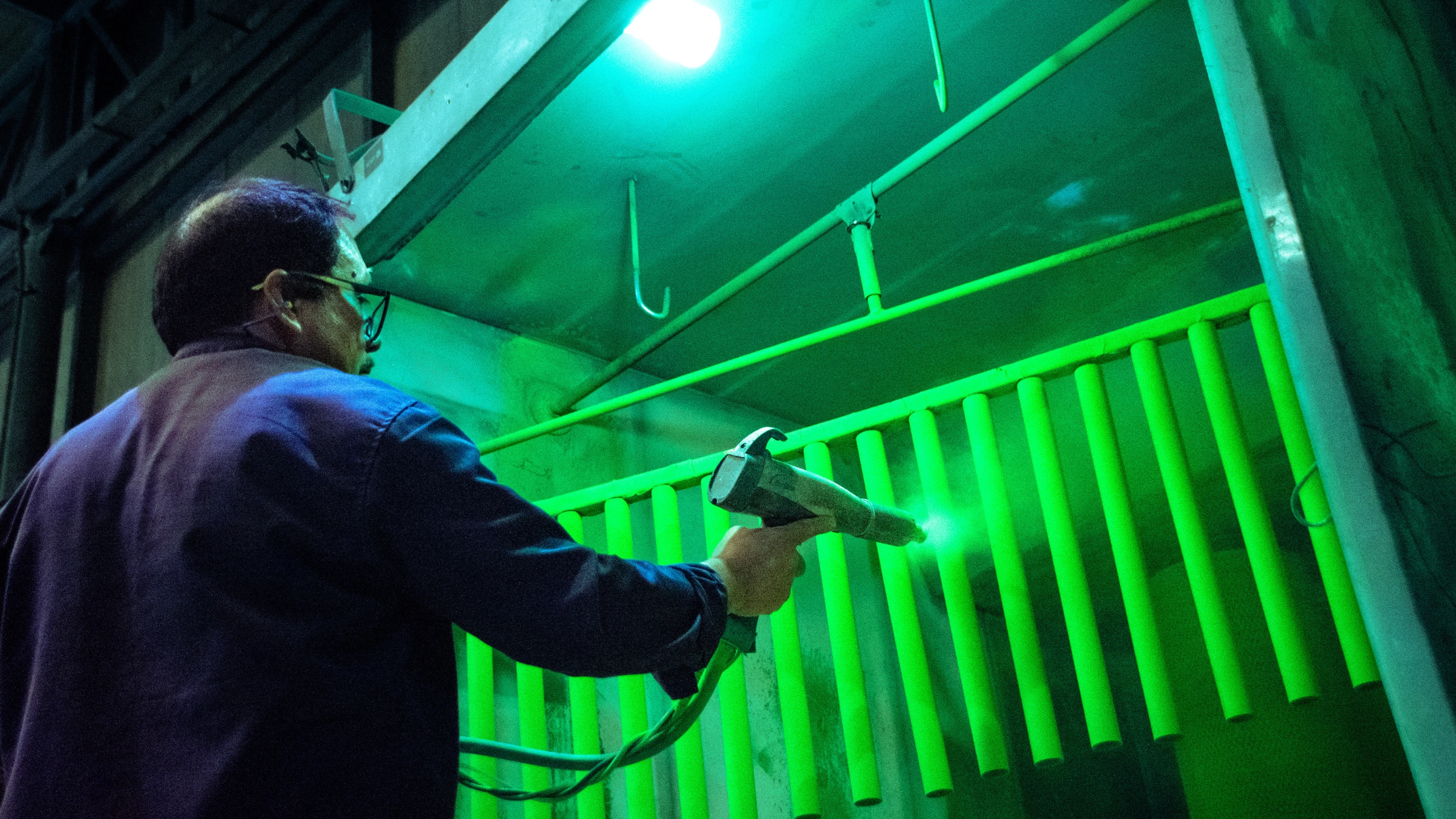 Operación industrial de EMYASA, con una persona trabajando junto a maquinaria iluminada en verde.